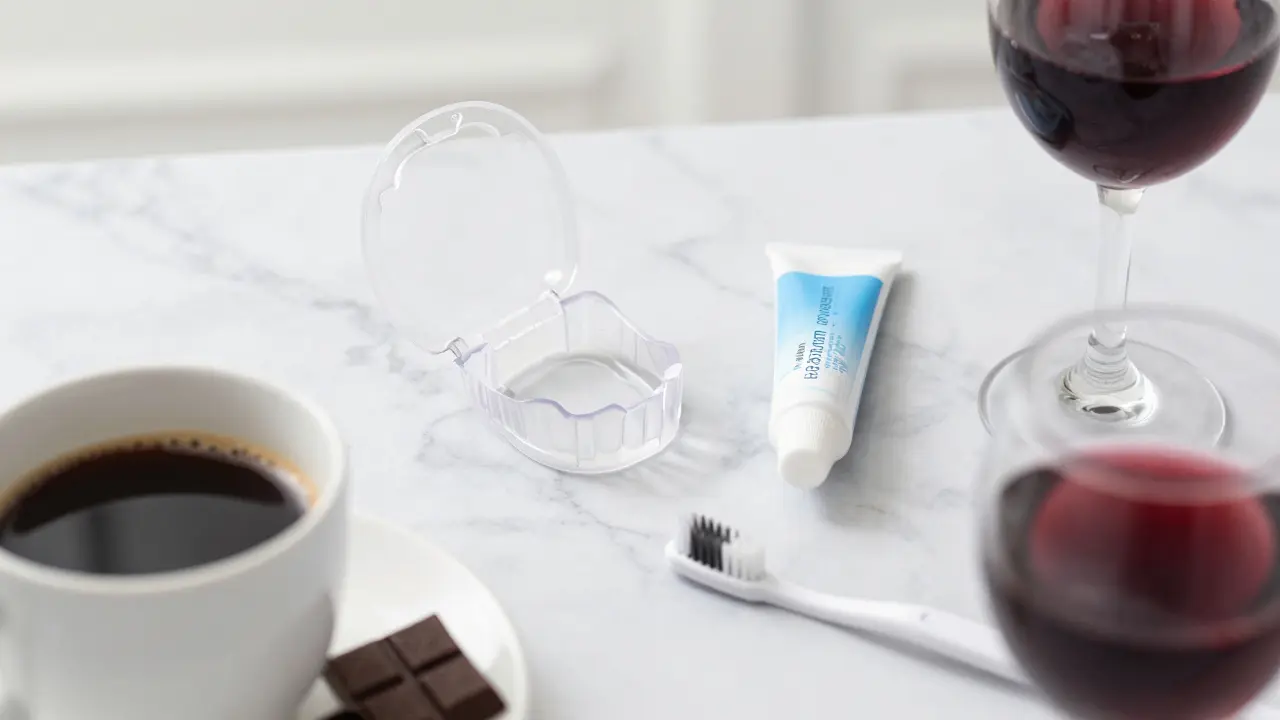 Home whitening trays with gel next to coffee and wine glasses